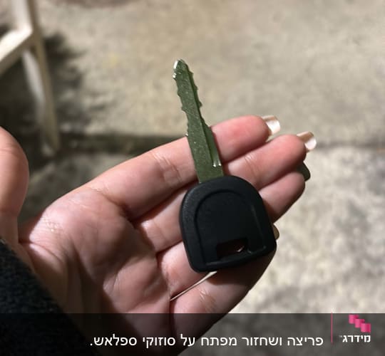 מפתח רכב מוחזק ביד על רקע כביש
